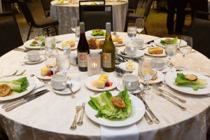 A table at the Online Journalism Awards Banquet at ONA22; plates with salad and bottles of wine are on the table.